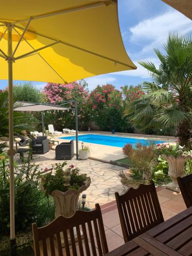 une terrasse avec un parasol jaune et une piscine dans l'établissement Villa paradis, à Fréjus