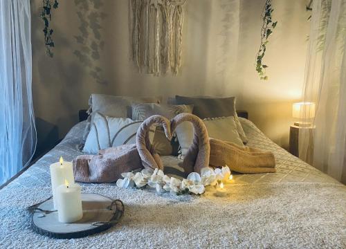 Una cama con dos velas y una cesta con forma de corazón en Suite romantique avec sauna et jacuzzi, 
