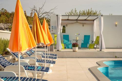 a group of umbrellas and chairs next to a pool at Rustic Villa Florice with a pool in Lećevica