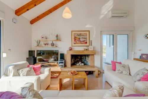 a living room with white furniture and a fireplace at Rustic Villa Florice with a pool in Lećevica