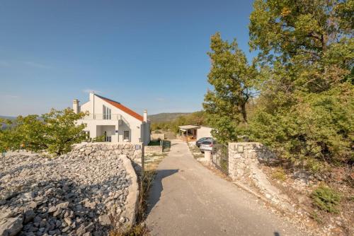 a house with a stone wall and a driveway at Rustic Villa Florice with a pool in Lećevica