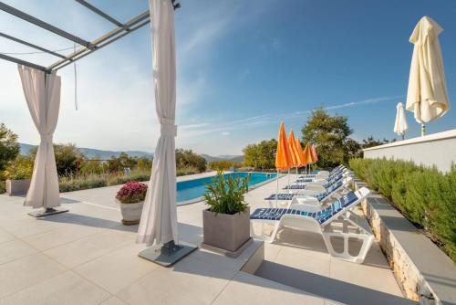 a pool with umbrellas and lounge chairs at Rustic Villa Florice with a pool in Lećevica
