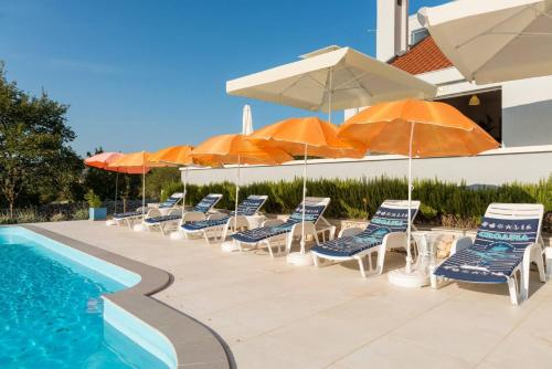 a group of chairs and umbrellas next to a pool at Rustic Villa Florice with a pool in Lećevica