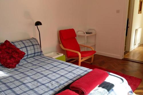 a bedroom with a bed and a red chair at Secluded self-contained Annexe near town centre in St Austell