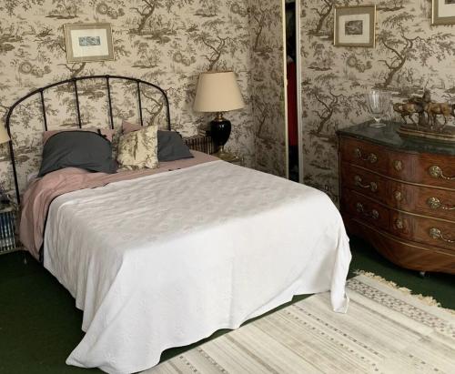 - une chambre avec un grand lit et une commode dans l'établissement Aux bonheurs des roses, à Valmont