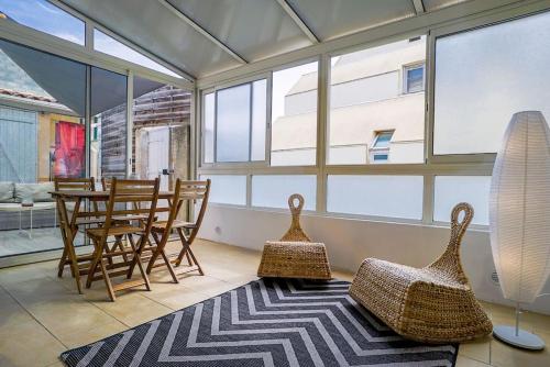 un salon avec des chaises, une table et des fenêtres dans l'établissement La Maison du Surfeur, T2, Clim, Terrasse, Pkg, Centre Ville, à Montpellier