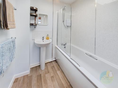 a white bathroom with a sink and a shower at Lovely Chalet - Welcome Holiday Park Dawlish warren in Bellaghy
