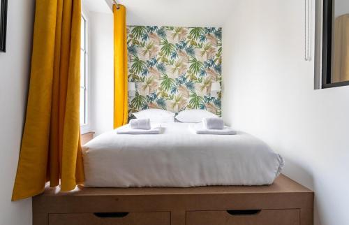 a bedroom with a bed with a yellow curtain at Lucelyne - Beau T2 rénové - Centre - Plage 400m in Dinard