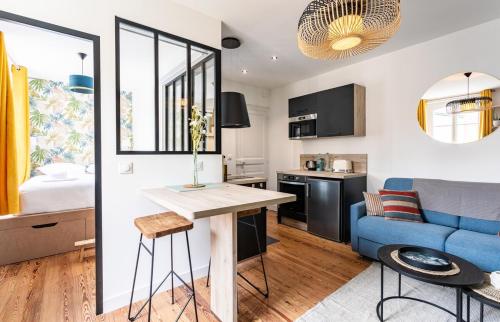 eine Küche und ein Wohnzimmer mit einem Tisch und einem blauen Sofa in der Unterkunft Lucelyne - Beau T2 rénové - Centre - Plage 400m in Dinard