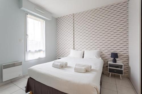- une chambre avec un grand lit blanc et des serviettes dans l'établissement L'Opale - Joli appartement avec jardin et garage, à Dinard