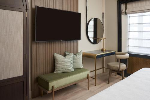 a hotel room with a tv and a chair and a desk at Hotel Vesper, Houston, a Tribute Portfolio Hotel in Houston