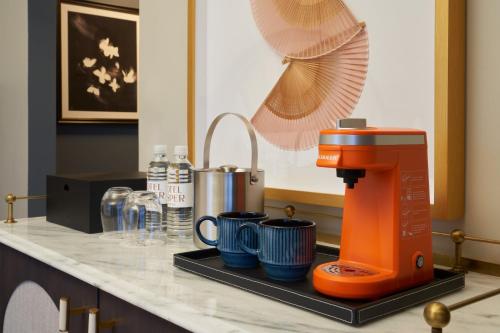 an orange coffee maker sitting on a counter with mugs at Hotel Vesper, Houston, a Tribute Portfolio Hotel in Houston