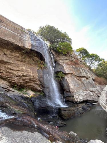 a waterfall on the side of a rocky cliff at Cosmic Mud House Kanthalloor in Kanthalloor