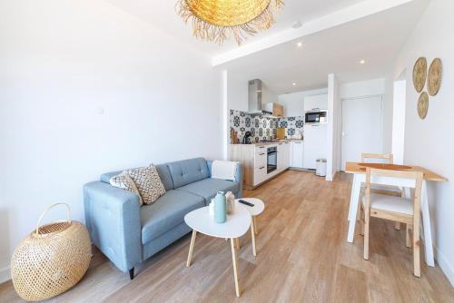 ein Wohnzimmer mit einem blauen Sofa und einem Tisch in der Unterkunft Les Pieds Dans L'Eau - Appartment 2 - Vue mer in Cancale