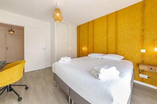 - une chambre avec un grand lit blanc et une chaise dans l'établissement L'Equinoxe, T2 de plain-pied dans résidence neuve., à Saint-Malo