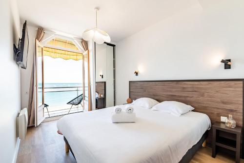 Les Pieds Dans L'Eau - Appartment 1 - Vue mer في كانكال: غرفة نوم مع سرير أبيض كبير مع نافذة كبيرة