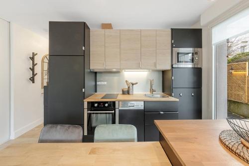 een keuken met zwarte apparatuur en een tafel bij CÔTÉ RIVIÈRE, appartement T2, terrasse & parking in Rennes