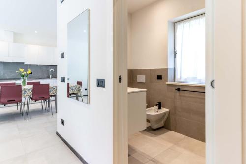 a bathroom with a toilet and a kitchen with a table at La Casa Azzurra, Levico Terme Ospitar in Levico Terme