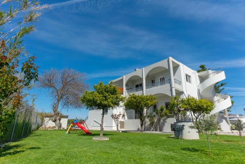 a white house with a yard with a playground at Marvinas seaside apartments, Earth apartment & Ocean jacuzzi apartment in Kremasti