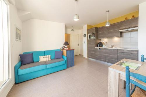 Les Oyats - Appartement 1 chambre - Balcon في سان كولوم: غرفة معيشة مع أريكة زرقاء ومطبخ