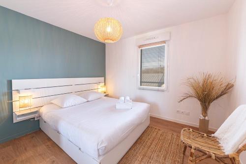 a bedroom with a large white bed and a chair at Le Magellan - logement neuf, parking, grand balcon in Dinard