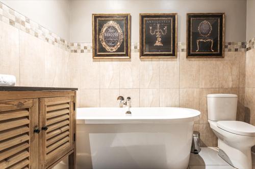 baño con bañera y aseo y cuadros en la pared en Tramonto House en Newcastle