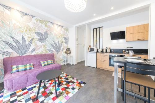 a living room with a purple couch and a kitchen at L'échapée- Bel appartement rénové et proche Gare in Rennes