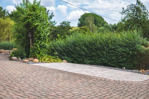 a brick walkway in a garden with bushes at Ferienwohnung Haus Biggi in Gransdorf