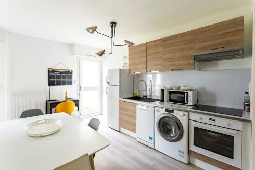 a kitchen with a washing machine and a table at Les Asturies - Appartement rénové - Cosy moderne in Rennes