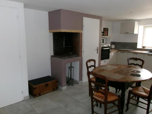 une cuisine avec une table et des chaises ainsi qu'une cuisine avec une cuisinière dans l'établissement LOGEMENT 4 PERSONNES, à Gréville-Hague