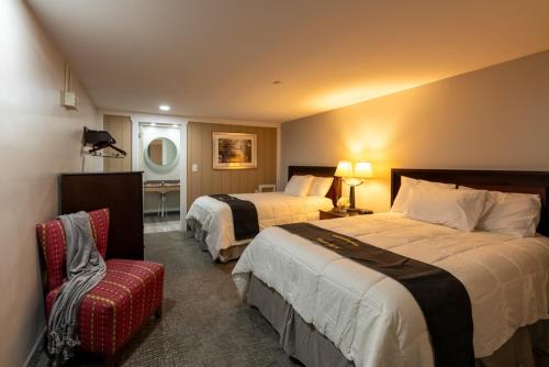 a hotel room with two beds and a chair at Lock Haven Grandview Hotel in Mill Hall