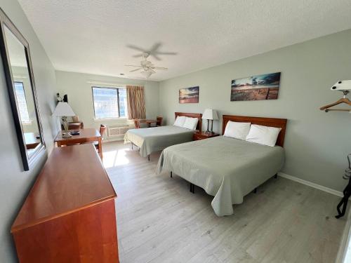 Sand Pebble Motor Lodge في بوينت بليزانت بيتش: غرفة فندقية بسريرين وطاولة