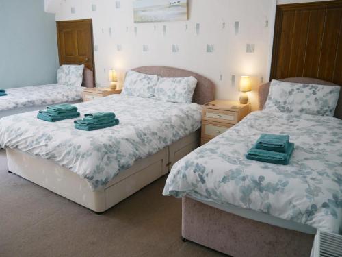 1 dormitorio con 2 camas y toallas verdes. en Rhostwarch Old Farmhouse Eglwyswrw, en Eglwyswrw
