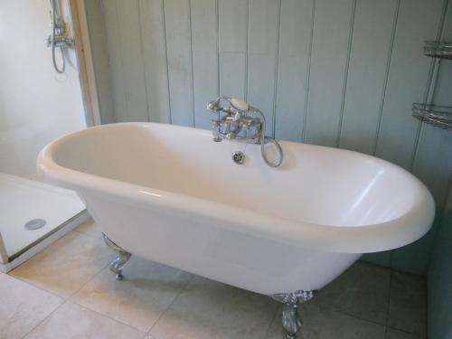 bañera blanca con grifo en el baño en Rhostwarch Old Farmhouse Eglwyswrw, en Eglwyswrw