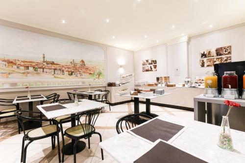 フィレンツェにあるアルベルゴ フィレンツェのテーブルと椅子が備わる大きな壁画のあるレストラン