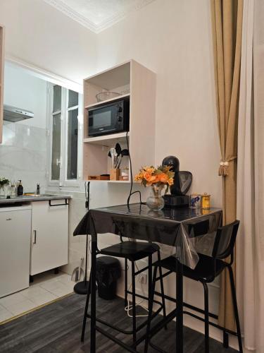 - une cuisine avec une table et des chaises noires dans la chambre dans l'établissement COSY BALI, à Bondy