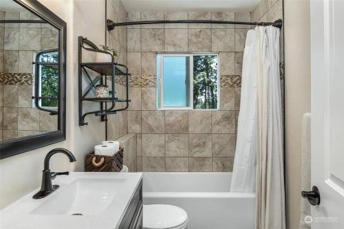 a bathroom with a tub and a sink and a mirror at Secluded 4BR Nestled in Woods-Hot Tub/Dog Friendly in Friday Harbor