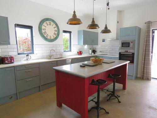 a kitchen with a large clock on the wall at Umber Cottage in Holsworthy