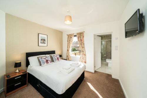 a bedroom with a bed and a flat screen tv at Pelshaven Cottage in Cornhill-on-tweed