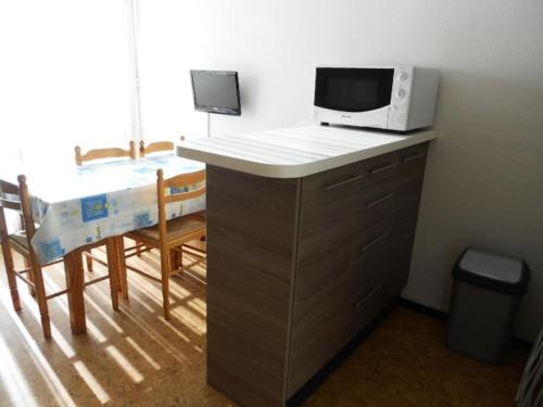 Il comprend une cuisine équipée d'un four micro-ondes et d'une table avec des chaises. dans l'établissement Résidence Hameau Du Soleil - APPARTEMENT 4 PERSONNES VIELLE-AURE MAE-3434, à Vielle-Aure
