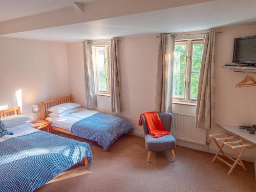 a bedroom with two beds and a chair and a television at By the River in Glasbury