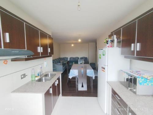a kitchen with a table and a white refrigerator at London Family home in Cochabamba