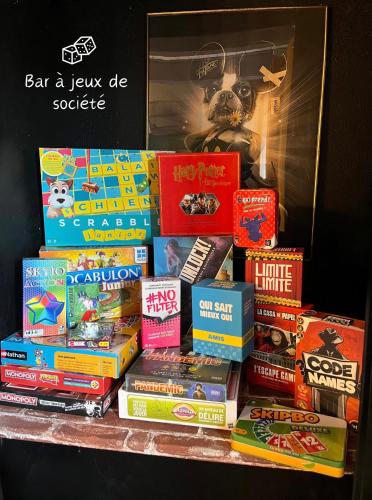 a pile of books sitting on top of a table at MAISON "Jungle House" 90 m2 BILLARD, RÉTROPROJECTEUR, BAR À JEUX , VINYLE, WIFI FIBRE, idéal PRO & FAMILLE à Montbrison in Montbrison