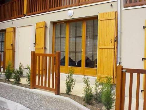 a building with wooden doors and a fence at Résidence Eugenie - Appartement 4 personnes au village de GUCHEN MAE-3464 in Guchen
