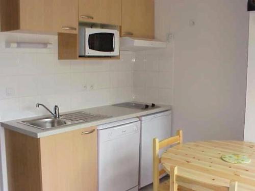 a kitchen with a sink and a microwave and a table at Résidence Eugenie - Appartement 4 personnes au village de GUCHEN MAE-3464 in Guchen