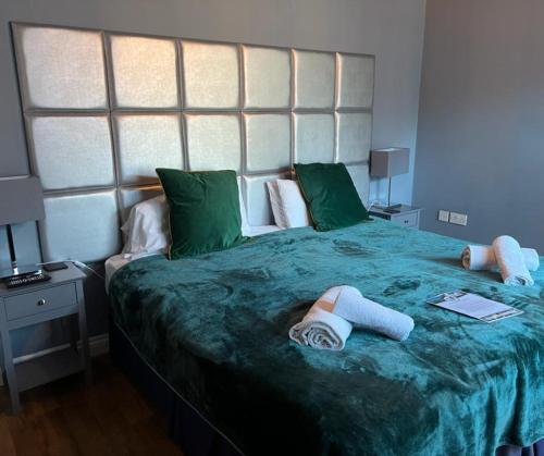 ein Schlafzimmer mit einem großen grünen Bett mit zwei Handtüchern darauf in der Unterkunft The Farmers Boy Inn Guest House in Longhope