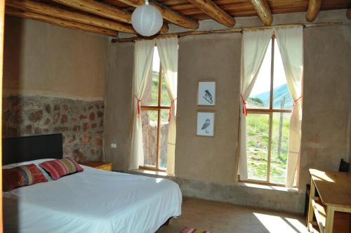 Schlafzimmer mit einem Bett und großen Fenstern in der Unterkunft Pampachayoq - Mountain retreat in Urubamba