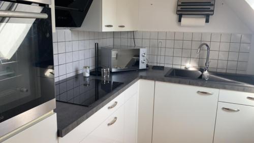 cocina con armarios blancos, fregadero y microondas en Zimmer in Wohnung, Monteure, Zentral,, en Enger
