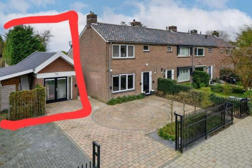 una gran casa de ladrillo con una flecha roja apuntando a ella en Gastenverblijf en Badhoevedorp