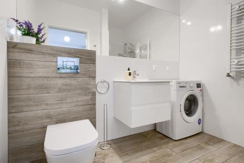 ein weißes Bad mit einer Waschmaschine in der Unterkunft ApartamentyPrzyMorzu Apartament z basenem i bawialnią in Kołobrzeg